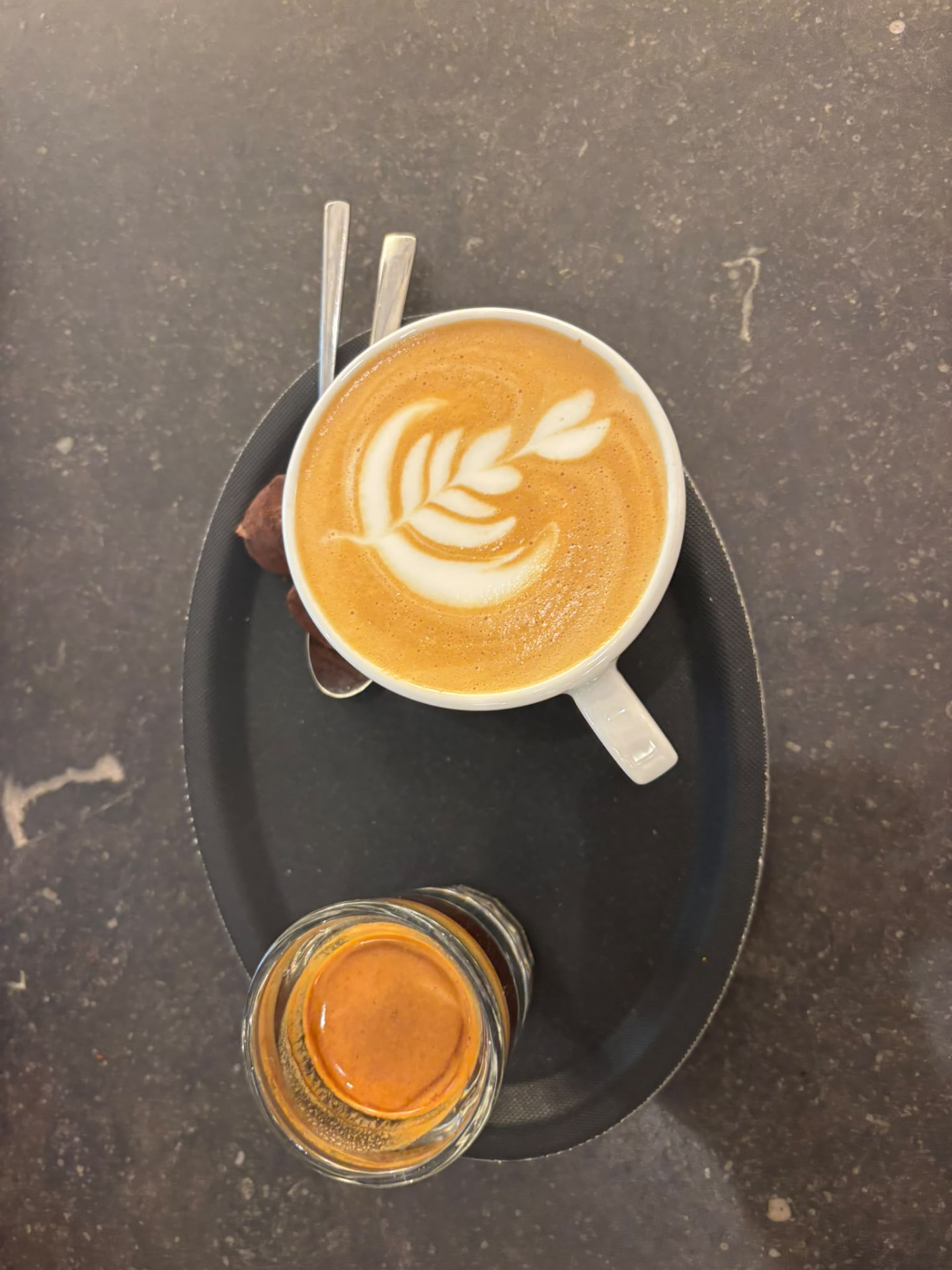 Cappuccino met latte art en een espresso op een dienblad